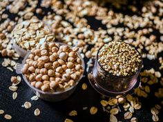 three small bowls filled with seeds on top of a black tablecloth covered in flakes