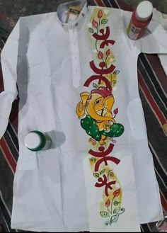 a white shirt with an image of a lion painted on it and some paintbrushes next to it