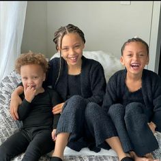 three children are sitting on a bed smiling