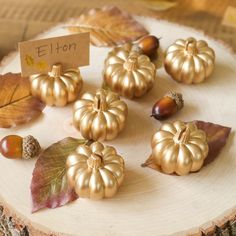 small gold pumpkins and acorns on a wood slice