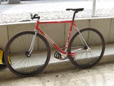 a red bike parked next to a wall