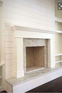 an empty living room with a fireplace and bookcases