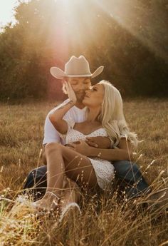 a man and woman sitting in the grass kissing