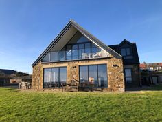 a house with large windows sitting on top of a lush green field