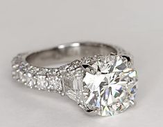 a diamond engagement ring is shown on a white surface with the center stone surrounded by small diamonds