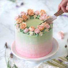 a person is cutting into a cake with flowers on the frosting and icing