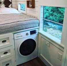 a washer and dryer in a small room next to a window with trees outside