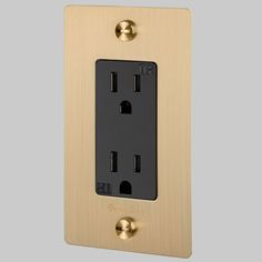 an electrical outlet with two black and gold outlets on the side, in a light wood finish