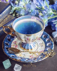 a tea cup and saucer with blue liquid in it