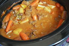 a crock pot filled with stew and carrots