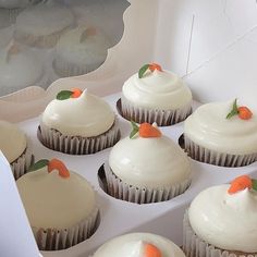 cupcakes with white frosting and carrot decorations in a cardboard box, ready to be eaten