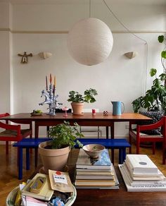 a dining room filled with lots of plants and books on top of a wooden table