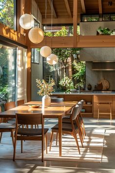 the dining room table is surrounded by wooden chairs and hanging lights in front of an open kitchen