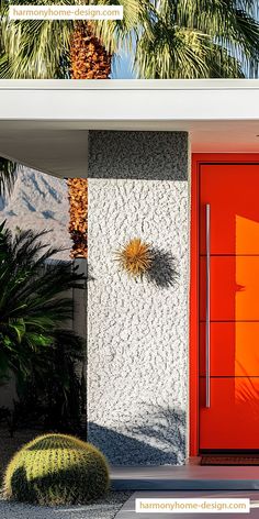 an orange door is in front of a white stucco house with palm trees on the side