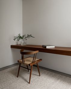 a wooden chair sitting in front of a desk with a plant on top of it