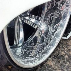 the front tire of a white car with intricate designs on it's rims