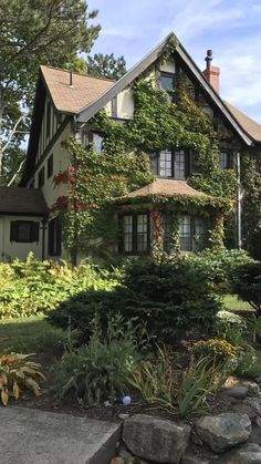 a house with ivy growing on the side of it's roof and landscaping around it