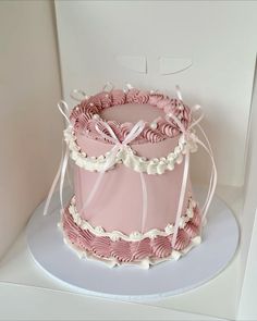 a pink and white cake sitting on top of a table