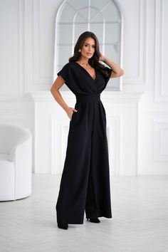 This stunning black jumpsuit is crafted from high-quality suiting fabric for a sleek and polished look. Featuring a deep V-neck and a double-layered bodice, it creates a chic, layered effect. The short sleeves resemble delicate wings, adding a touch of lightness and grace to the design. The waistline is accentuated to visually enhance your figure, while the wide-leg pants feature pleats for extra volume and comfort. A zipper at the back ensures a perfect fit. Ideal for formal events, parties, or any special occasion, this jumpsuit offers both style and comfort. Length: 145 cm Shoes To Wear With Jumpsuit Wedding, Plus Size Wedding Jumpsuit, Jumpsuit Outfit Formal, Wide Leg Pants Outfit Dressy, Mother Of The Bride Pants Outfit, Wide Leg Jumpsuit Formal, Alternative Wedding Outfit, Mother Of The Bride Jumpsuit, Pants Outfit Dressy