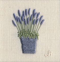 blue flowers are in a small pot on the white cloth, and one is stitched