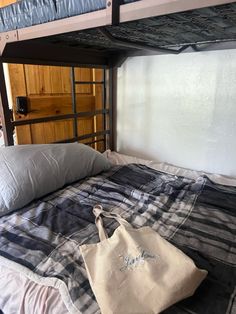 a white bag sitting on top of a bed next to a wooden wall and ladder