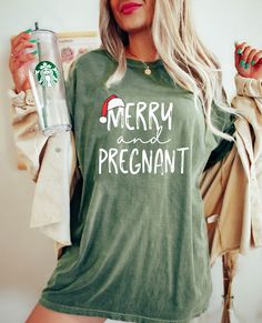 a woman wearing a green shirt with merry and pregnant written on it