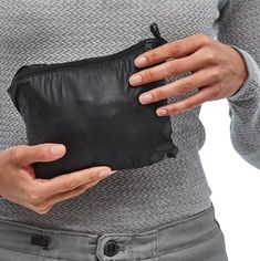 a woman holding a black leather pouch in her hands and showing it to the camera