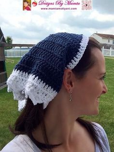 a woman wearing a blue and white crochet hat in front of a house