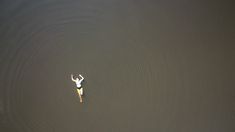 a person on a surfboard in the middle of a body of water with their arms up