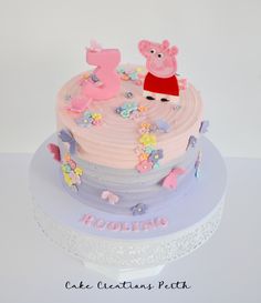 a pink and blue cake with pep the pig topper on it's side