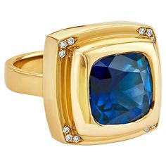 Introducing a blend of opulence: the Chocolate Gold Blue Sapphire Ring, a luxurious masterpiece exuding elegance and allure. Appropriately named "Sapphire Temptation," this statement gold ring features mesmerizing blue tones that mirror the richness of the finest treats. Experience guilt-free splendor as this exquisite blue sapphire ring adorns your finger with unparalleled sophistication. The cushion-cut blue sapphire, nestled within the lavish contours of yellow gold, radiates pure magnificence. Enhanced by sparkling white diamonds at each corner, its charm reaches dazzling new heights. Whether as a personal indulgence or a treasured gift, this ring embodies the essence of decadence and refinement. The striking Chocolate Gold Blue Sapphire Ring effortlessly takes center stage. With its d Gold Blue Sapphire Ring, Statement Gold Ring, Chocolate Gold, Deep Royal Blue, Blue Sapphire Ring, Gold Statement Ring, Blue Sapphire Rings, Guilt Free, Blue Tones