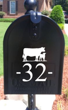 a black mailbox with a cow on it and the number 32 in front of a house