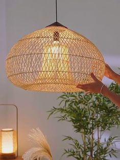 a person is holding up a light fixture in the air above a table with plants and candles