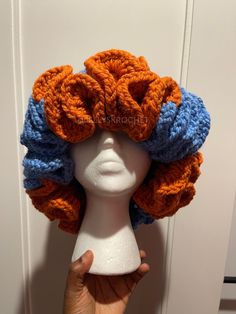 a white mannequin head with an orange and blue crochet hat on it