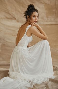 a woman sitting on the ground wearing a white dress