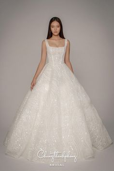 a woman in a white wedding dress standing against a gray background