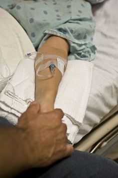 a person laying in a hospital bed with an iv tube wrapped around their arm and hand