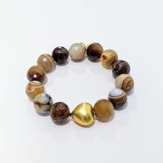 This Ro & Gieo bracelet features stunning banded agate beads paired with a chunky 24 karat gold-plated brass heart. The unique combination of materials offers a luxurious and trendy look, making it the perfect accessory for any occasion. The banded agate beads provide a natural and earthy touch, while the gold-plated heart adds a touch of elegance. Elevate your style with this exquisite bracelet. Ro & Gieo Banded Agate Bead and 24 karat gold-plated 100% brass heart chunky bracelet Beads - 16 mm Chunky Bracelets Beads, Jasper Bead Bracelet, Radiant Beauty, Bracelet Wrist, Chunky Bracelet, Page One, Cuff Bangle Bracelet, Chunky Bracelets, Banded Agate