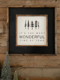 there is a framed sign on the wall next to some christmas trees and a small fir tree