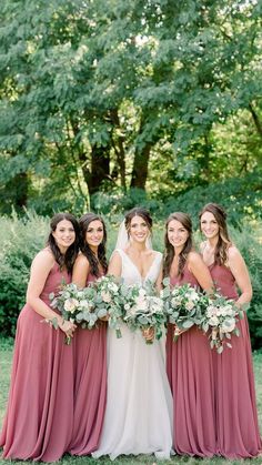 the bride and her bridesmaids pose for a photo in front of some trees