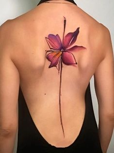 the back of a woman's shoulder with a flower tattoo on it