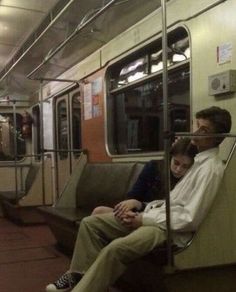 two people sitting on a subway train next to each other