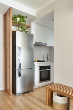 a stainless steel refrigerator freezer sitting inside of a kitchen next to a wooden bench