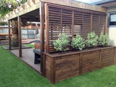 a wooden deck with plants on it and a grill in the back ground next to it