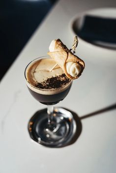 a glass filled with chocolate and marshmallows on top of a white table