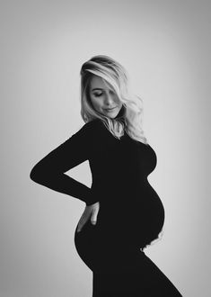 a pregnant woman poses for a black and white photo with her hands on her hips