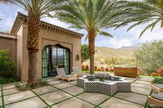 an outdoor living area with palm trees and patio furniture in front of a stucco building