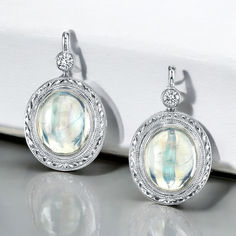 Once in a Blue Moon! Very fine quality moonstone cabochons are featured in these beautiful earrings. These moonstones are highly transparent with fine blue adularescence or "billowing light" effect, which gives moonstone its mysterious nature. Each moonstone is bezel set in a beautifully hand engraved, 18k white gold mounting, accented with a sparkling diamond. Handmade by our Master Jewelers in Los Angeles. Formal Round Moonstone Earrings, Silver Oval Earrings With Gemstone Accents, White Moonstone Drop Earrings, Oval Moonstone Earrings For Gift, White Oval Moonstone Earrings, Blue Moonstone Drop Earrings, Round Moonstone Cabochon Earrings, Luxury Bezel-set Moonstone Jewelry, Once In A Blue Moon