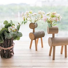 three wooden toy animals sitting on top of a table next to flowers in vases