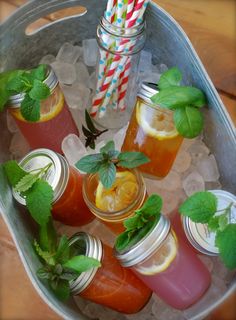 there are many drinks in mason jars with straws and mint leaves on the table